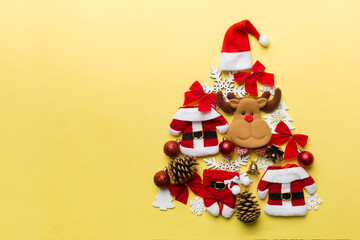 Christmas tree made from colored suit santa decoration on colored background, view from above. New Year minimal concept with copy space