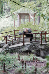 Sports girl doing stretching with her leg lifted on the railing of the bridge in the park