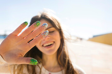 Smiling woman showing palm with multi-colored glitter