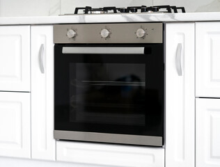 Gas stove with and embedded electric oven at brand new modern white kitchen