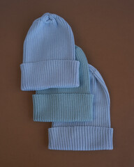 vertical photo on a white background red green pink and blue hats are knitted from wool yarn