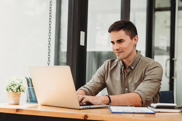 Handsome businessman in modern office looking on laptop