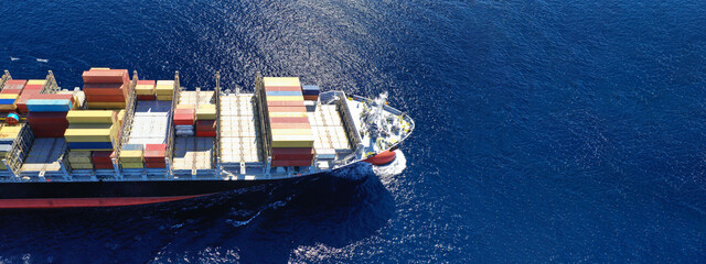 Aerial drone ultra wide top down photo of container cargo tanker ship carrying truck-size colourful containers in deep blue open ocean sea  - obrazy, fototapety, plakaty