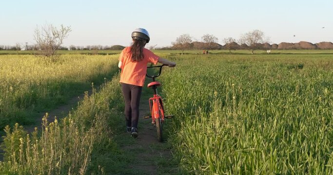 Child with a bike in the meadow. A young child walk with a bike on the village road in summer.