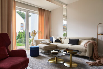 Creative living room interior composition with beige sofa, glass coffee table, carpet on the floor and glamorous accessories. Template.