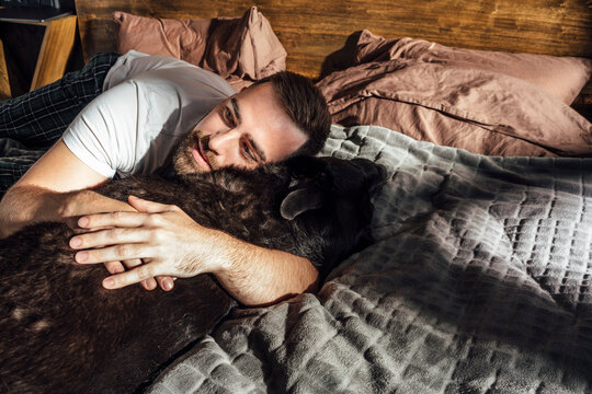 Mid adult man hugging dog on bed