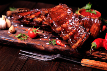 Grilled pork ribs with spices and vegetables on a wooden background
