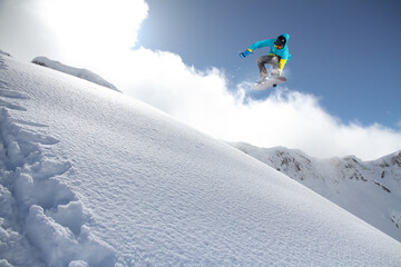 A jumping snowboarder in the mountains. Snowboarding, winter extreme sport.