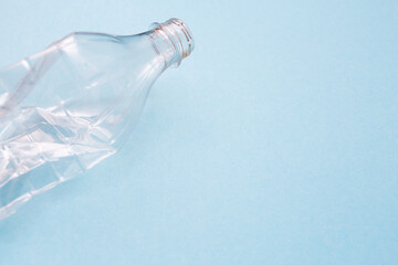 Empty crumpled plastic bottle on blue background with place for text. Copy space. Recycling concept. Ecology problems. Flat lay.