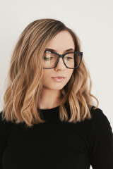 Portrait of a young blond woman with long bob haircut wearing eyeglasses with black frame. Eyewear....