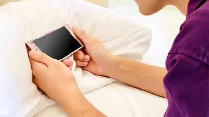 枕の上でスマホを横にして見る人の手