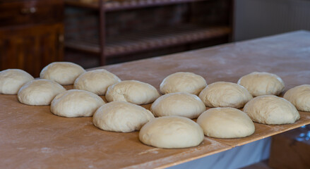 Fresh raw dough balls on the wooden board. Homemade bread or pizza. Preparing traditional homemade bread or pizza. Baking process.