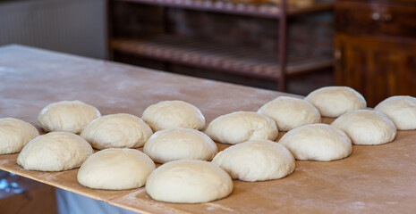 Fototapeta na wymiar Fresh raw dough balls on the wooden board. Homemade bread or pizza. Preparing traditional homemade bread or pizza. Baking process.