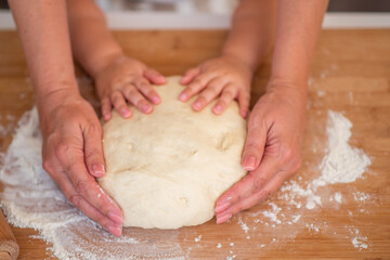 Grandmother and granddaughter using cookie cutter to cut dough in shapes. Little cute girl and senior grandma in preparing cookies for christmas. Grandchild with old granny cooking in kitchen.