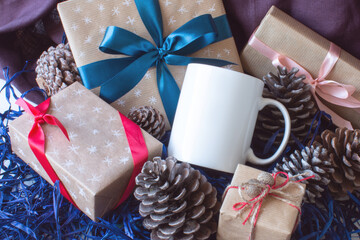 White mug with gifts and fir cones. White cup mockup. New Year's and Christmas. Winter holidays. Wrapped gifts.