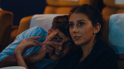 Attractive cheerful young caucasian woman watching horror movie in cinema theater. Lifestyle entertainment concept.