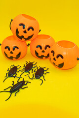 Halloween pumpkins and plastic cockroaches on yellow background. Halloween concept.