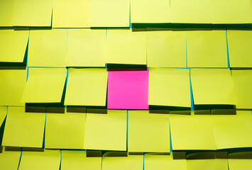 Creative layout made of yellow sticker notes with one pink note in a middle. Top view, flat lay. Minimal greetings, celebration or work task concept. With copy space.