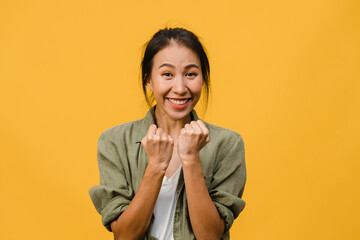 Fototapeta na wymiar Young Asia lady with positive expression, joyful and exciting, dressed in casual cloth and look at camera over yellow background. Happy adorable glad woman rejoices success. Facial expression concept.