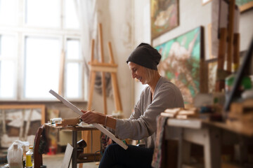 Middle age artist woman working for painting in the studio. Workshop or art class.
