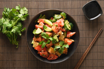 Chinese crispy spicy eggplant with cucumber, garlic, tomatoes, fresh cilantro leaves in oyster sauce and black vinegar on black background. Tasty Chinese appetizer and Asian food. Top view. Flat lay.
