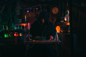 Fototapeta na wymiar portrait of alchemist magician in interior of dark laboratory workshop with flasks and equipment