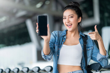 happiness cheerful smiling asian female traveller hand gesture show smartphone screen at airport terminal,asian female woman smiling  hand point present show smartphone blank scrren for your ideas 