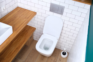 White toilet bowl with open lid standing in bathroom background