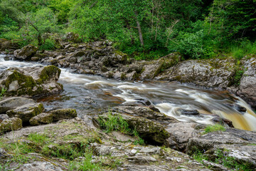 Naklejka na ściany i meble Water flowing over rocks in a river