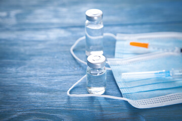 Syringes, mask and vials on the blue background.