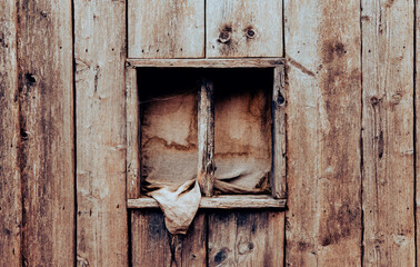 Old ancient wooden window with dirty linen curtain. Log cabin outside wall. An old window in a wooden house. Close-up. Background. Texture.