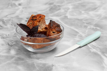 Grilled pork in a bowl with kitchen knife.