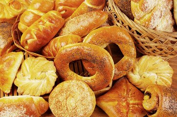 Baked bread rolls, pretzels, biscuits on a wooden table.