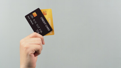 Hand is holding two credit card in black and gold color isolated on grey background.