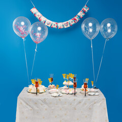 A table with desserts and party decorations, with balloons to celebrate the gender reveal of the...