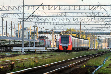 Front view of modern russian intercity high speed passenger train on railroad at sunset, freight train on background. Commercial suburban transportation concept