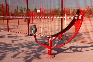 The training apparatus is wrapped in striped red and white barrier tape. Restrictions due to coronavirus. Empty urban sports ground.