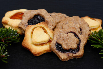 christmas cookies and fir branch lying on black shale at christmas time.