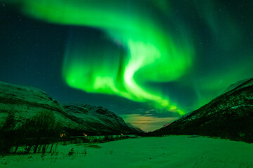 Nordlichter in Troms, Norwegen. Aurora Borealis spiegelt sich im Fjord und leuchtet über den schneebedeckten Bergen. the lady dance in the sky, northern light