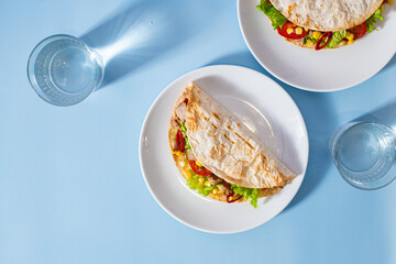 corn tortilla stuffed with meat and vegetables on a blue background. Taco