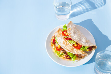 corn tortilla stuffed with meat and vegetables on a blue background. Taco