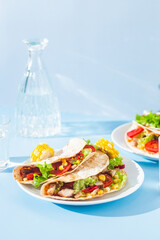 corn tortilla stuffed with meat and vegetables on a blue background. Taco