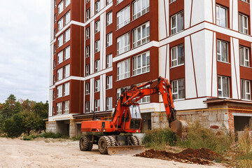 Construction site with a decorated house and an excavator in the foreground
