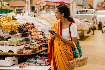 Young indian woman using mobile phone during shopping in eastern market