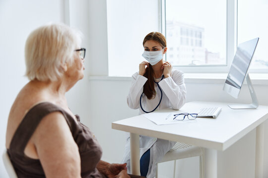 elderly woman wearing a medical mask communicates with the doctor medical office