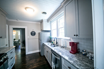 A small cottage kitchen with gray cabinets and dark hardwood floors in a short-term rental house
