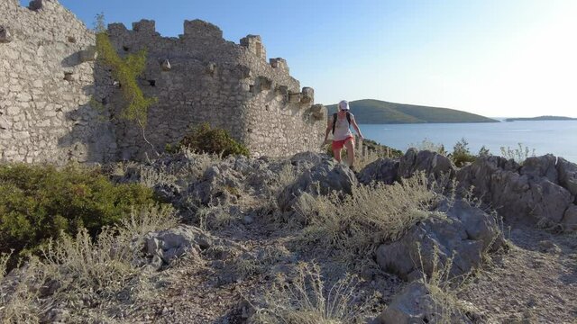 Woman on the wall of Ostrica in Croatia. Aerial view from Bedem Grebastica historic defensive wall, also called CHINESE WALL. Grebastica town in Sibenik-Knin County on the coast of Adriatic sea.