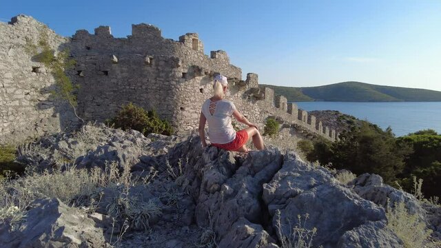 Woman waving a Croatian flag on Wall of Ostrica also called CHINESE WALL. Grebastica village in Sibenik-Knin County. Also called Bedem Grebastica historic defensive wall of Croatian-Ottoman wars.