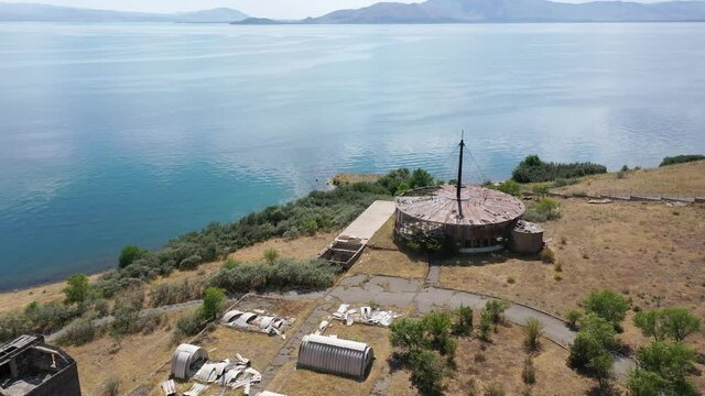 Aerial view abandoned, destroyed building near lake. Drone fly over empty building near lake. Ecology problem. Sevan lake, Armenia.