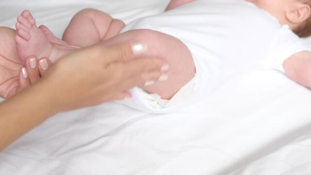 Mother gives massage to her newborn baby. Prevention of joint dysplasia. Pediatrics concept. 